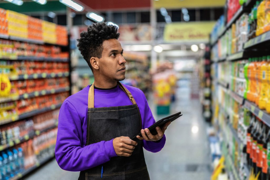 Homem trabalhando analisando as gôndolas do mercado