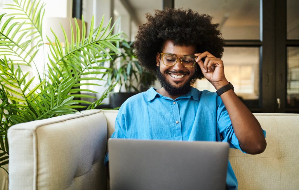 Homem com a mão no óculos olhando para o notebook