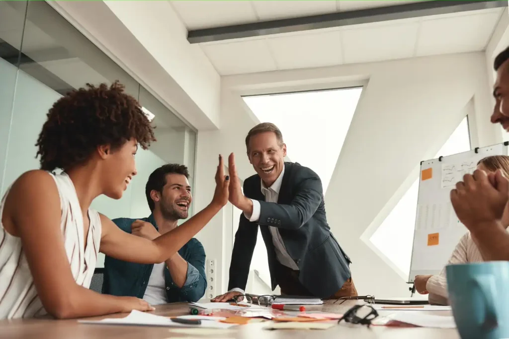 Colaboradores comemorando em uma reunião de campanha de incentivo no ambiente de trabalho, demonstrando motivação e entusiasmo.